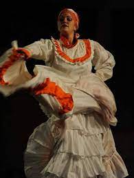 Bomba dancer waves long white skirt with orange edge.