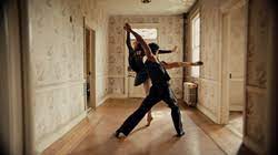 Two ballet dancers partner in a main hall way of a house.