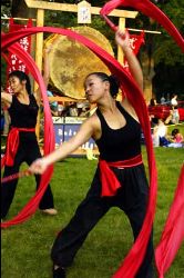 Dancers wearing black and a red belt, dance with red fabrics