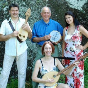Four people pose for photo. Three of them hold musical instruments.