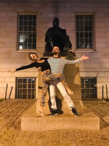 Two tango dancers poste in front of statue at Harvard.