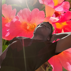 Dancer leans back with hand behind head into enlarged flowers in the background.