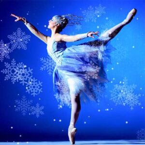 Ballerina in arabesque against blue background dotted with lacy snowflakes.