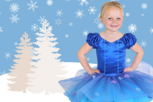 Toddler in a bun and a blue tutu stands with hands on hips in front of a blue and white winter scene.