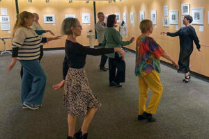 Six people learn a dance step from an instructor in front of them.