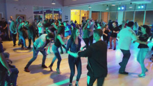 Crowd dances in a large ballroom.