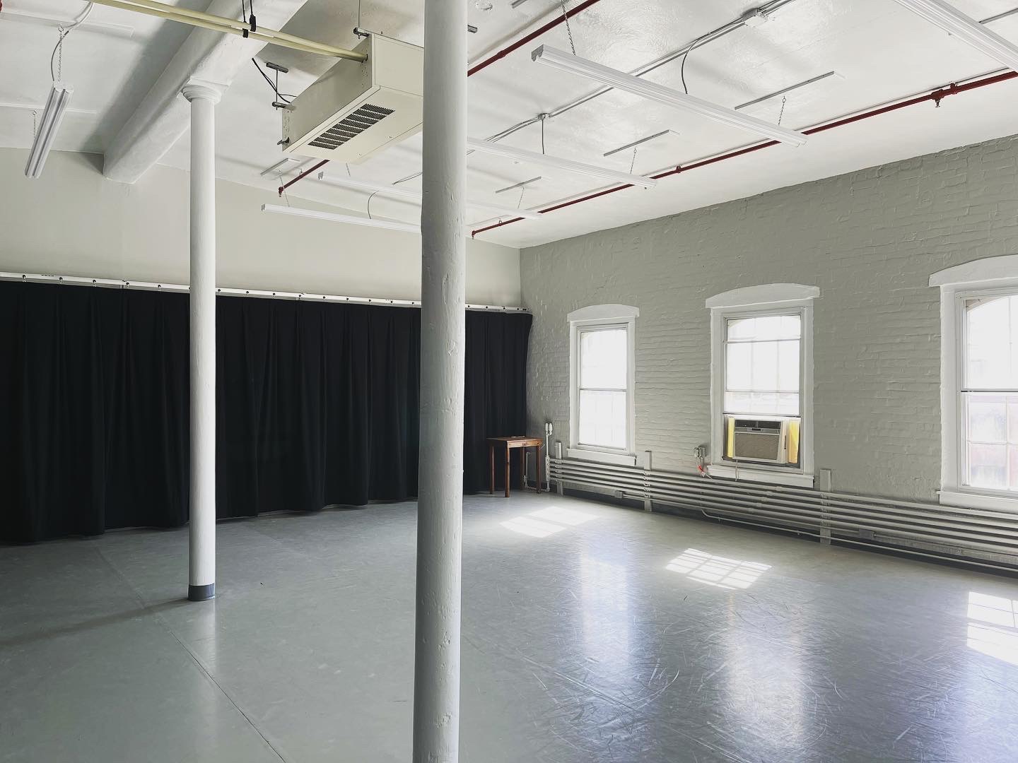 Picture of Studio 414; grey marley floor, white walls and bright windows.
