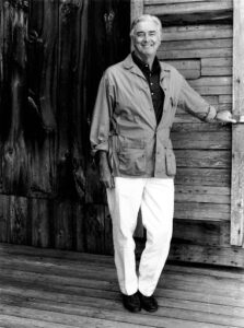 Black and white image of Neil standing with one hand at one of the Jacob's Pillow's doors.