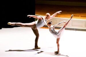 Two dancers in arabesque facing each other.
