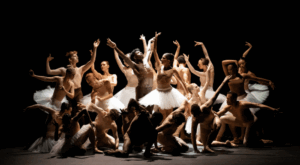 Many dancers gather together with nude tops and white tutus and form an elegant circle while every dancer holds a different position.