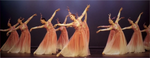 Multiple young dancers bend upper body sideways and extend one leg to the same side.