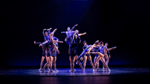 Tulsa ballet dancers in blue costumes and executing two large lifts in groups.