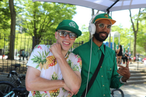 Two artists in a green palette wearing glasses and standing side by side smiling.