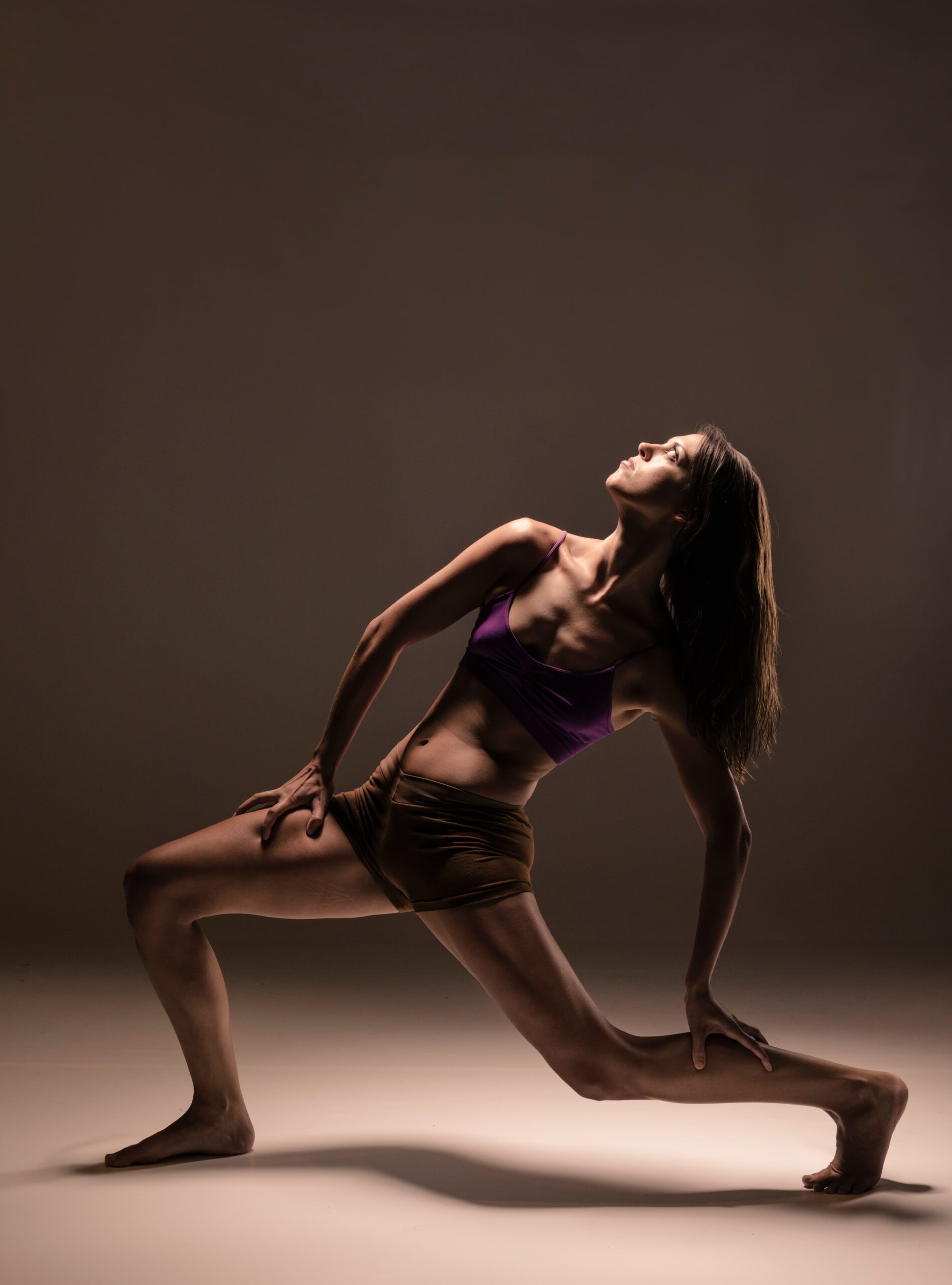 Dancer in a lunge under a dim spotlight