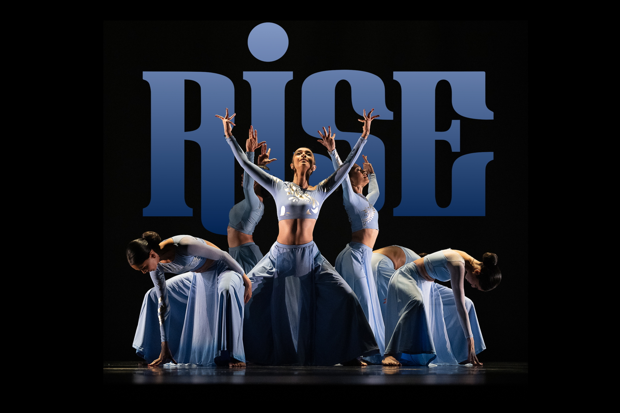 Dancers stand onstage in a circle, alternating some in a squat looking down, others reaching up to the sky. Dancers are in flowy blue pants and matching tight blue longsleeve tops. The word "RISE" is overlayed in the background